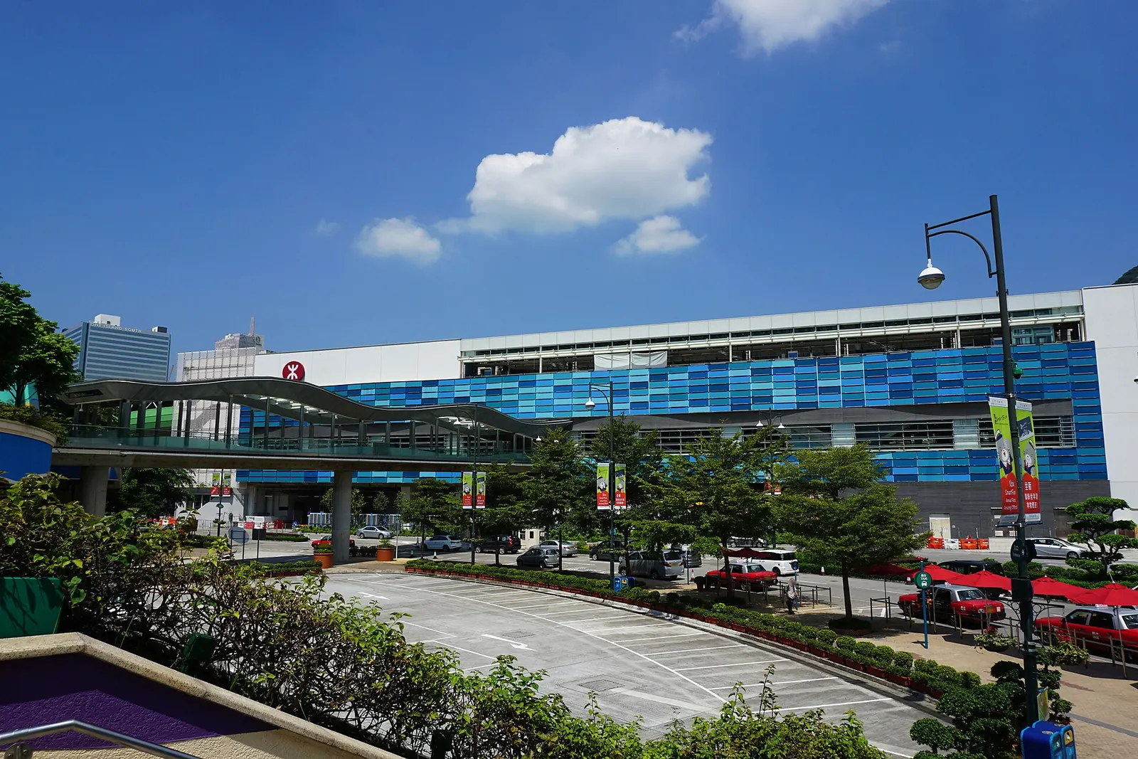 The blue-tiled front of Ocean Park MTR station beside a footbridge